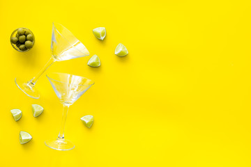 Cocktail concept. Martini glasses near olives and lemon on yellow background top-down copy space