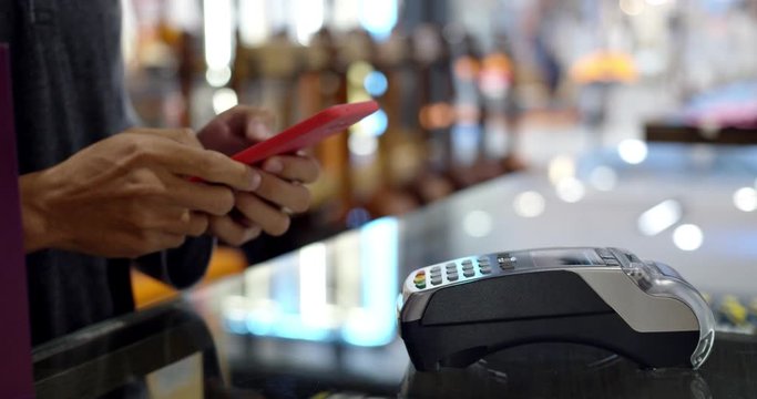 Young muslim man use smartphone paying over contactless transaction machine