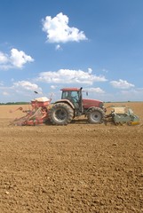 Obraz premium Semis mais avec semoir 32 rangs de 4m et outil ottavioli (tasseligne) à l'avant. Ciel nuageux