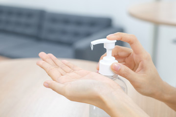 Woman hands using wash hand sanitizer gel pump dispenser. Clear sanitizer in pump bottle, for killing germs, bacteria and virus...