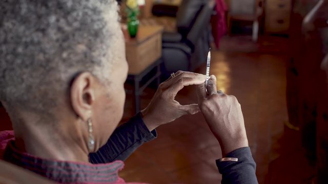 African American old woman preparing to give herself an insulin injection