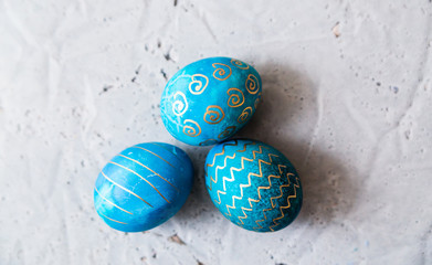 Eggs painted in blue and with a gold pattern on a concrete background.