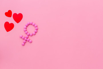 Gender Venus symbol made of contraceptive pills, near heart sign - woman health concept - on pink background top-down copy space