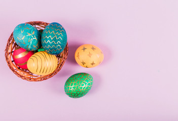 Colored easter eggs in a wooden basket on a purple background