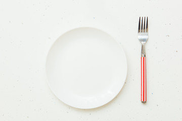 Empty plate and simple fork on white background. Top view
