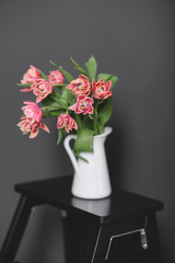 A bouquet of pink peony tulips in a white jug.