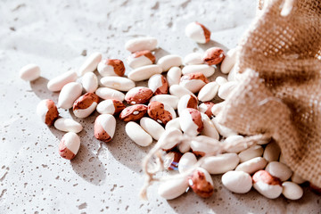 small  beans, haricot, white pea, white kidney  in a bag sackcloth isolated on concrete background