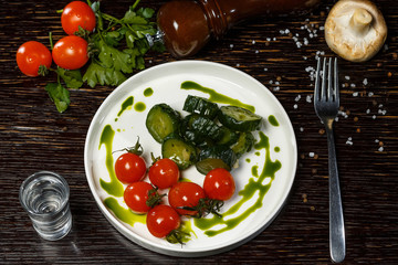  Pickles and pickled tomatoes on a white plate, a vodka appetizer.
