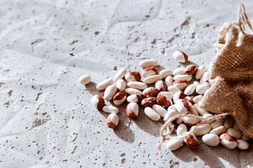 small  beans, haricot, white pea, white kidney  in a bag sackcloth isolated on concrete background