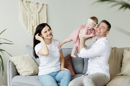 Young happy beautiful family is having fun at home. Cute wife husband and one year old baby girl are together.