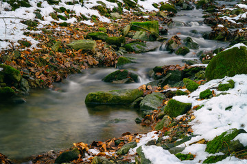 Fototapeta na wymiar Flowing small river in winter.