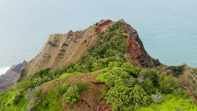 Inspiring aerial 4K view over the exotic island coastline formed by high winding ridges and deep narrow gorges. Sun enlights the tops of the rocks. Vibrant blue ocean looks smooth and calm. Hawaii,USA