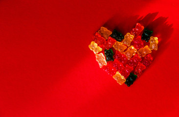 Heart shaped colored gelatins on red background