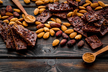 Homemade chocolate. Pieces, nuts on wooden table copy space