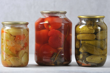 glass jar with an iron lid with canned red tomatoes and cucumbers
