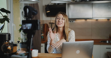Happy young attractive blonde makeup blogger recording new vlog video with professional camera at home slow motion.