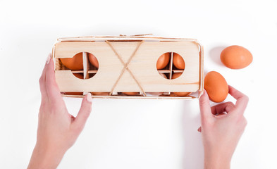 Fototapeta premium Female hands hold 10 natural fresh brown eggs in eco-friendly wooden packaging