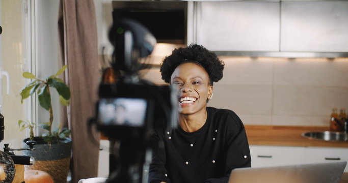 Happy young successful female black vlogger making new video for blog using professional camera at home slow motion.