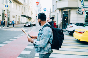 Carefree male tourist using smartphone and map in city