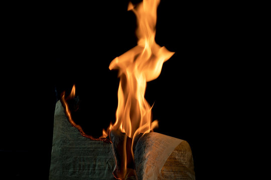Document being burned against black