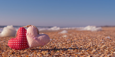 Image of a soft toy in the shape of a heart on the beach.