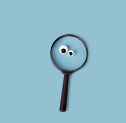 magnifying glass with google eyes on blue background. magnifier loupe - search symbol. minimal...