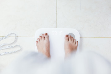 feet standing on electronic scales for weight control. Measurement instrument in kilogram for a...