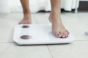 feet standing on electronic scales for weight control. Measurement instrument in kilogram for a...