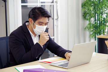 Young business man using laptop and wear mask to prevent the corona virus outbreak. 