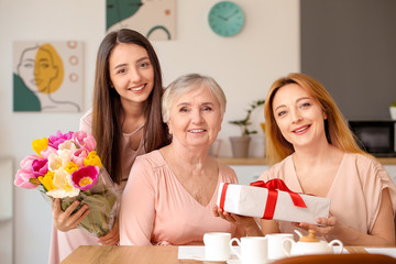 Mature woman with her adult daughter, mother and gift at home
