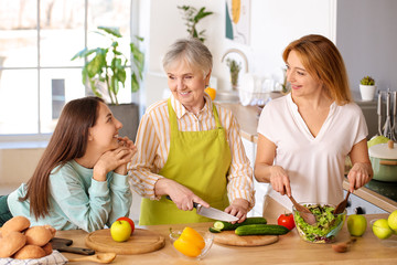 Mature woman with her adult daughter and mother cooking together at home
