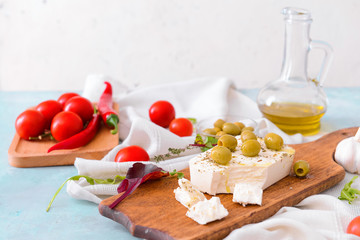 Board with tasty feta cheese, olives and spices on table