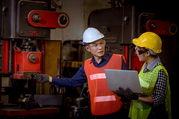 Engineer and worker industry factory wear safety uniform working and discussion detail about machine work by detail in laptop on hand control machine in factory.