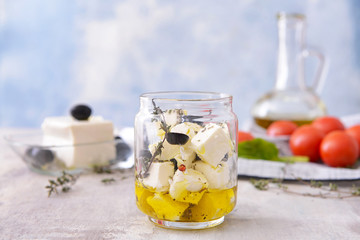 Jar with tasty feta cheese with olives, oil and spices on table