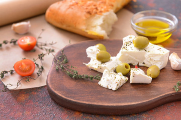 Tasty feta cheese with olives and spices on table