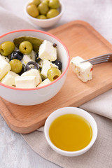 Tasty feta cheese with olives and oil on table