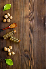 Nutmeg oil - perfume ingredient - on wooden background top-down copy space