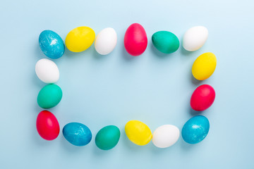 Frame of multicolored easter eggs on blue background. Easter composition. Copy space. Mockup