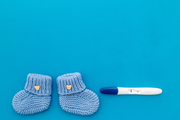 Positive pregnancy test. Baby boy concept with blue accessories on blue background top-down copy space