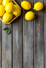 Ripe lemons in tray on dark wooden backgroud top-down frame copy space