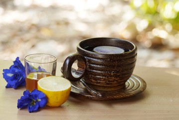 Wooden  cup of  herbal  tea on wooden table and spoon with  Butterfly pea flowers and honey  , selective focus.