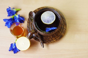 Wooden  cup of  herbal  tea on wooden table and spoon with  Butterfly pea flowers and honey  , selective focus.