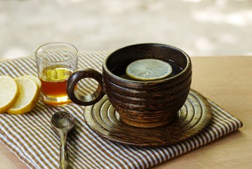 Wooden  cup  of herbal  tea  on wooden table  with lemon and honey , selective focus.