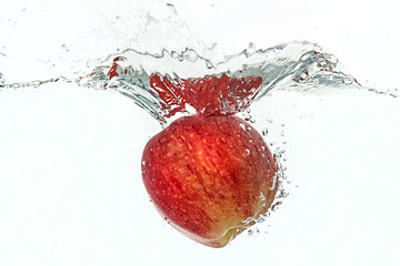 Red apple falling in water with a splash.