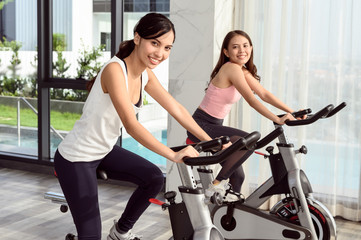 Fototapeta na wymiar Two smiling young woman workout in the gym