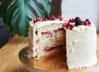Two halfs of a vanilla sponge cake made from natural ingredients decorated with red and violet berries
