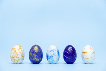 Three easter trendy colored classic blue and golden decorated eggs on blue background. Happy Easter...