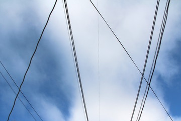 Interweaving of wires and cables against the blue sky with clouds. Industrial city landscape