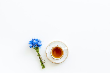 Summer tea party. Cup near cornflowers bouquet on white background top-down copy space