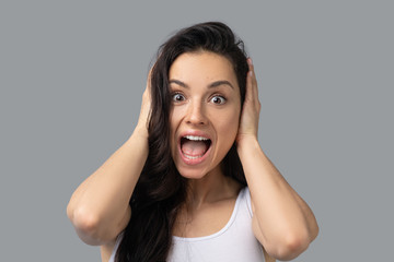 Pretty brunette girl in awhite top looking shocked